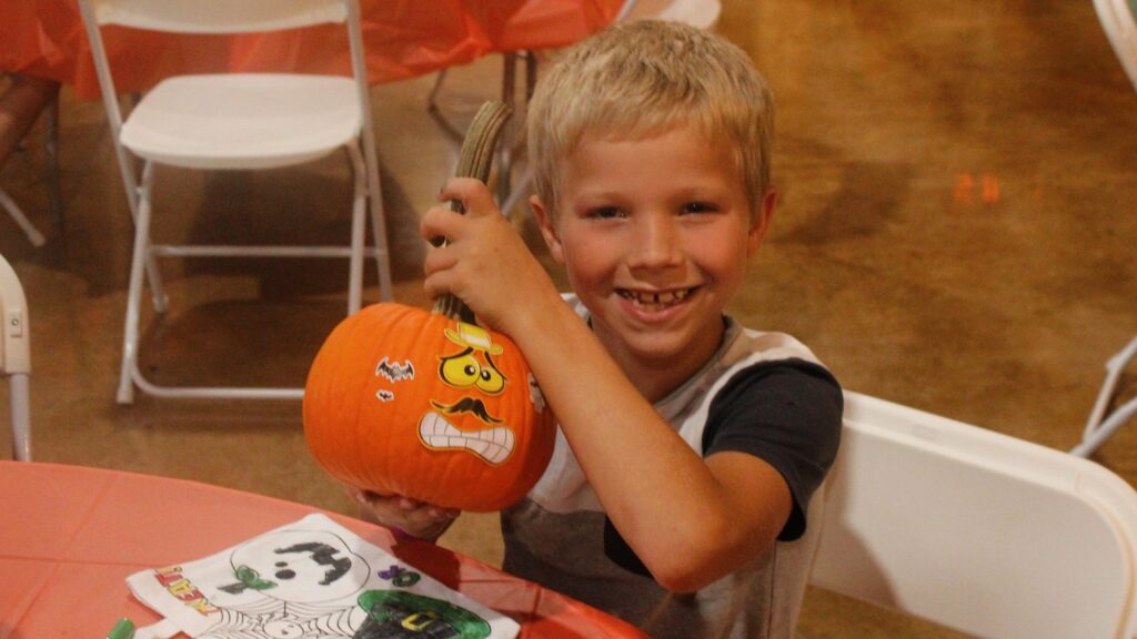 A boy holding a sticker-covered pumpkin