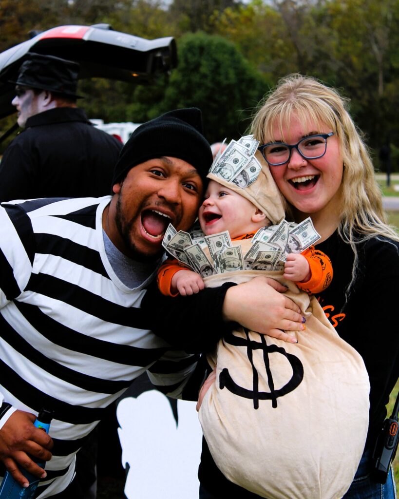 A family in matching costumes, the baby dressed as a money bag
