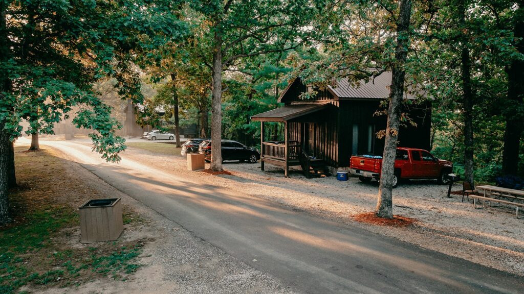 A cabin with a covered porch and picnic table beside the resort road.