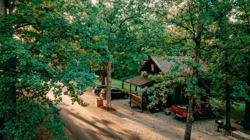 A cabin and its porch seen through the oak canopy above the resort road.