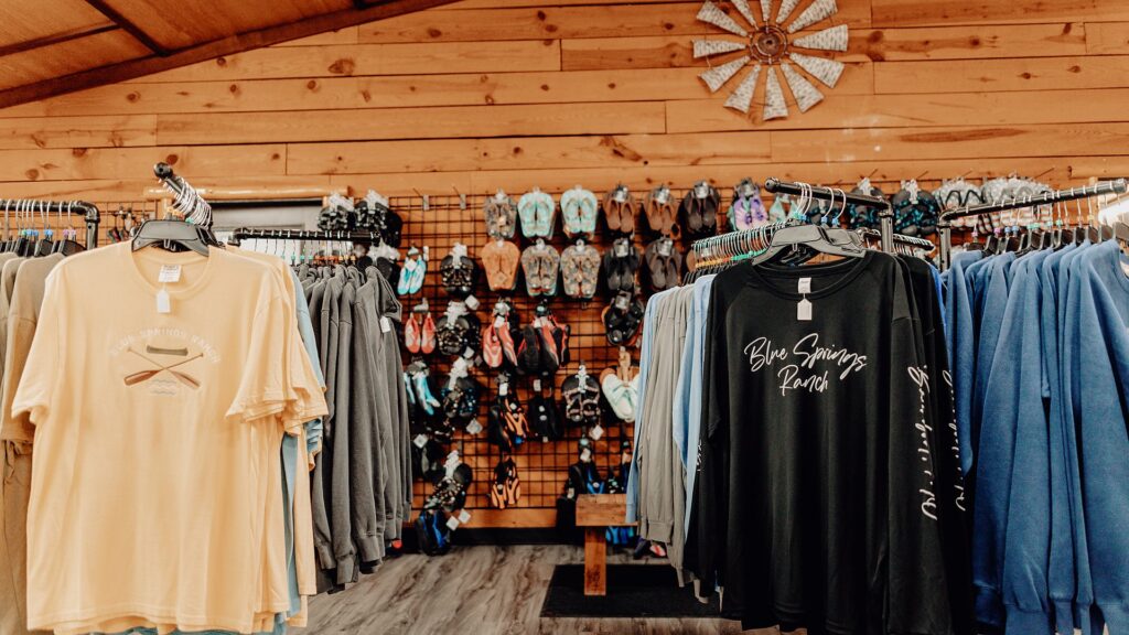 Shirts and footwear displayed across the camp store's back wall.
