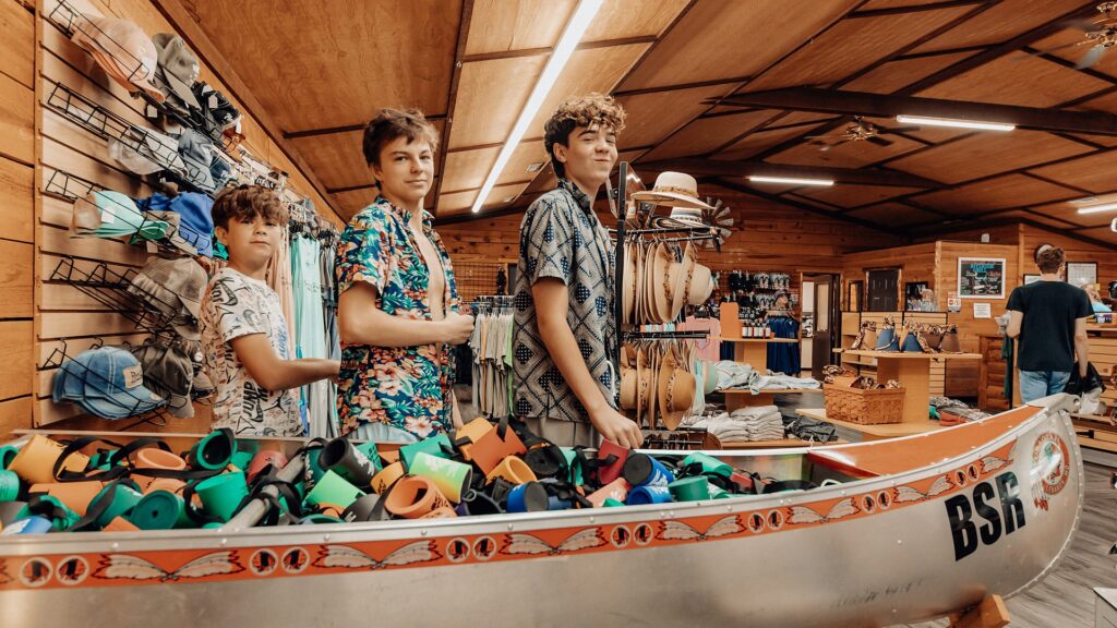Guests browsing the camp store beside a canoe filled with water shoes.