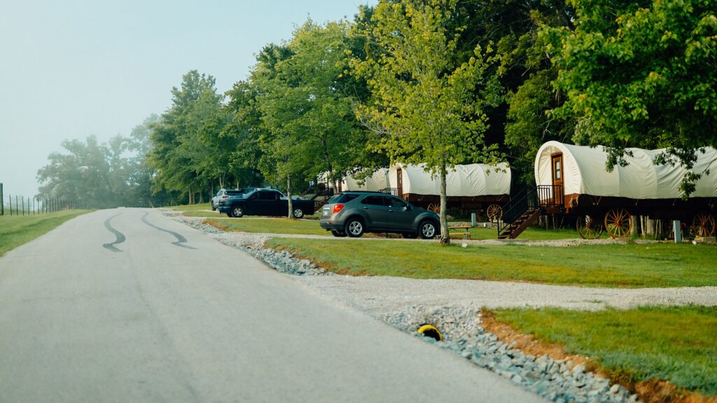A row of canvas-topped Conestoga wagons along the road, each with its own steps and deck.