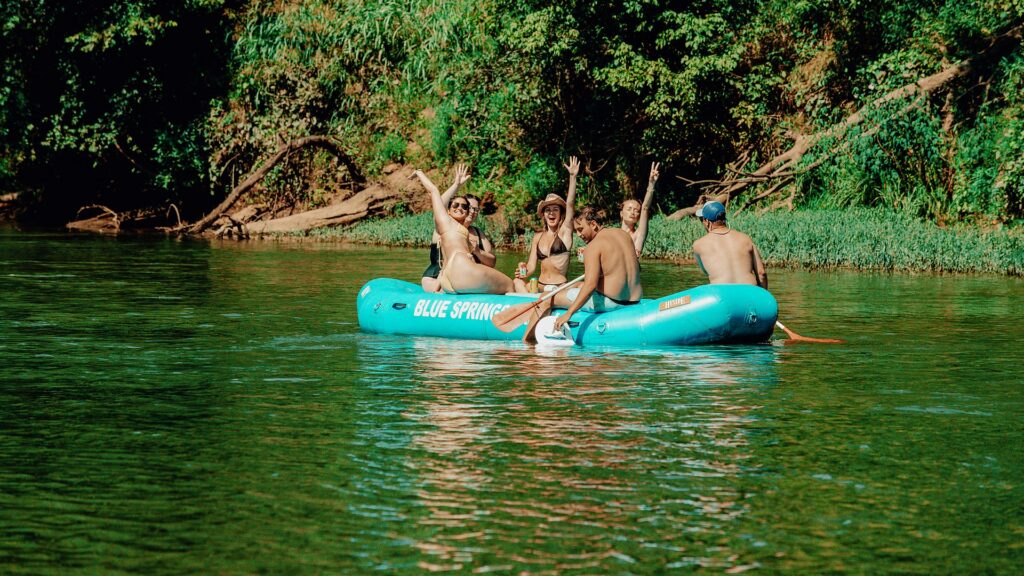 A group cheering with their arms up in a Blue Springs Ranch raft.