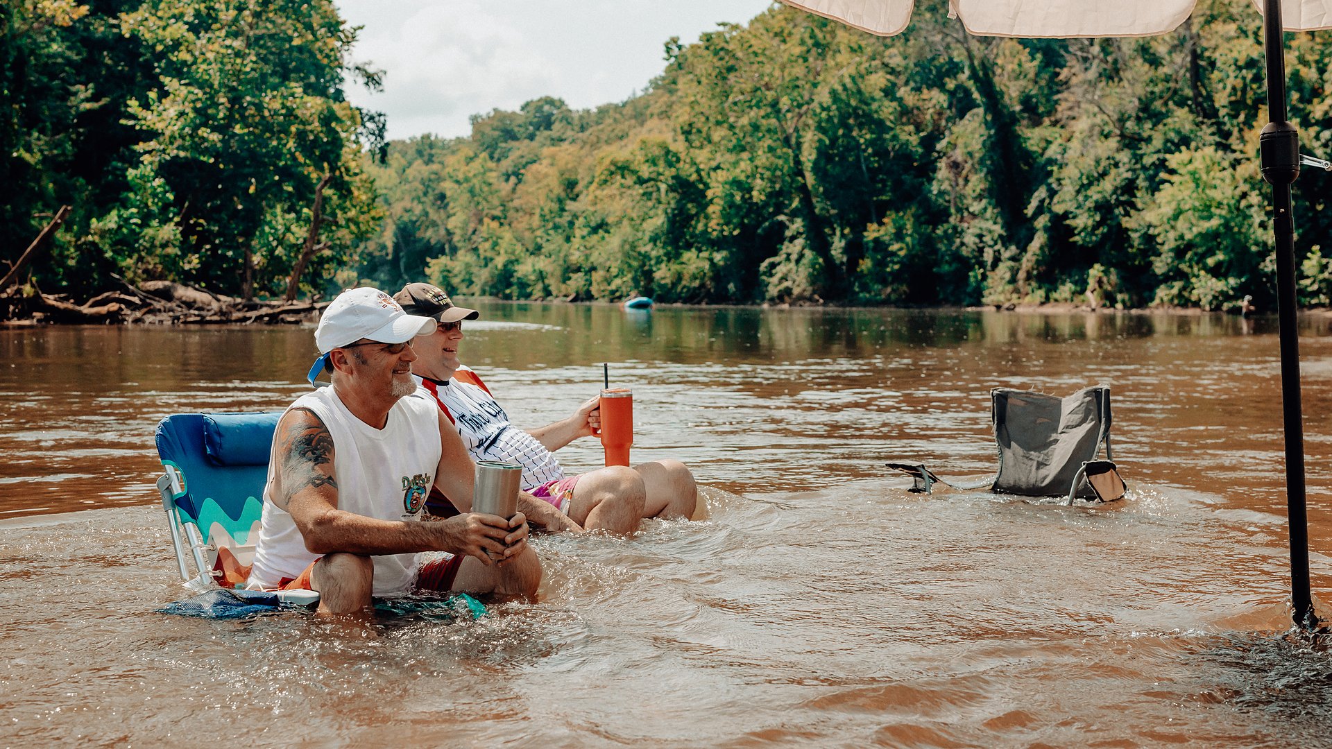 Guests relaxing in camp chairs set right in the shallow river.