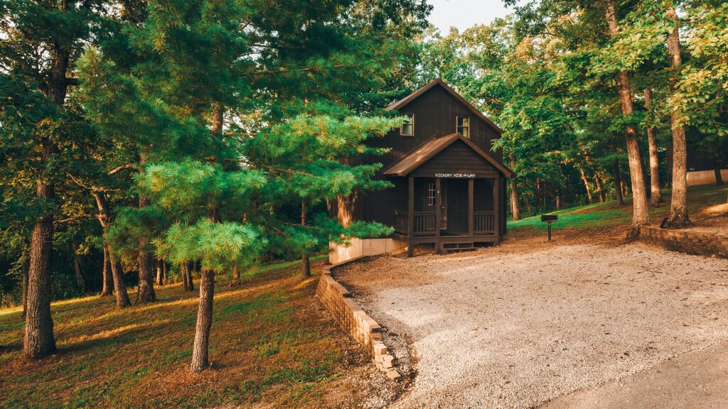 The Hickory Hide-A-Way cabin among the pines at the top of its gravel drive.