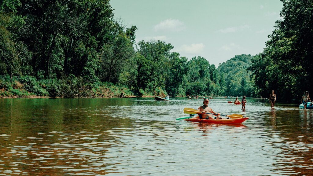 A kayaker on a calm reach of the river with other floaters behind.
