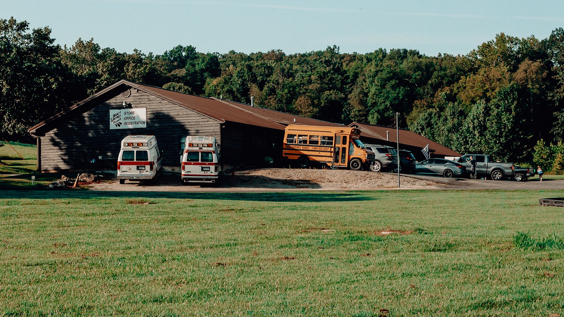 The registration office with shuttle vans and a bus parked outside, seen across the lawn.