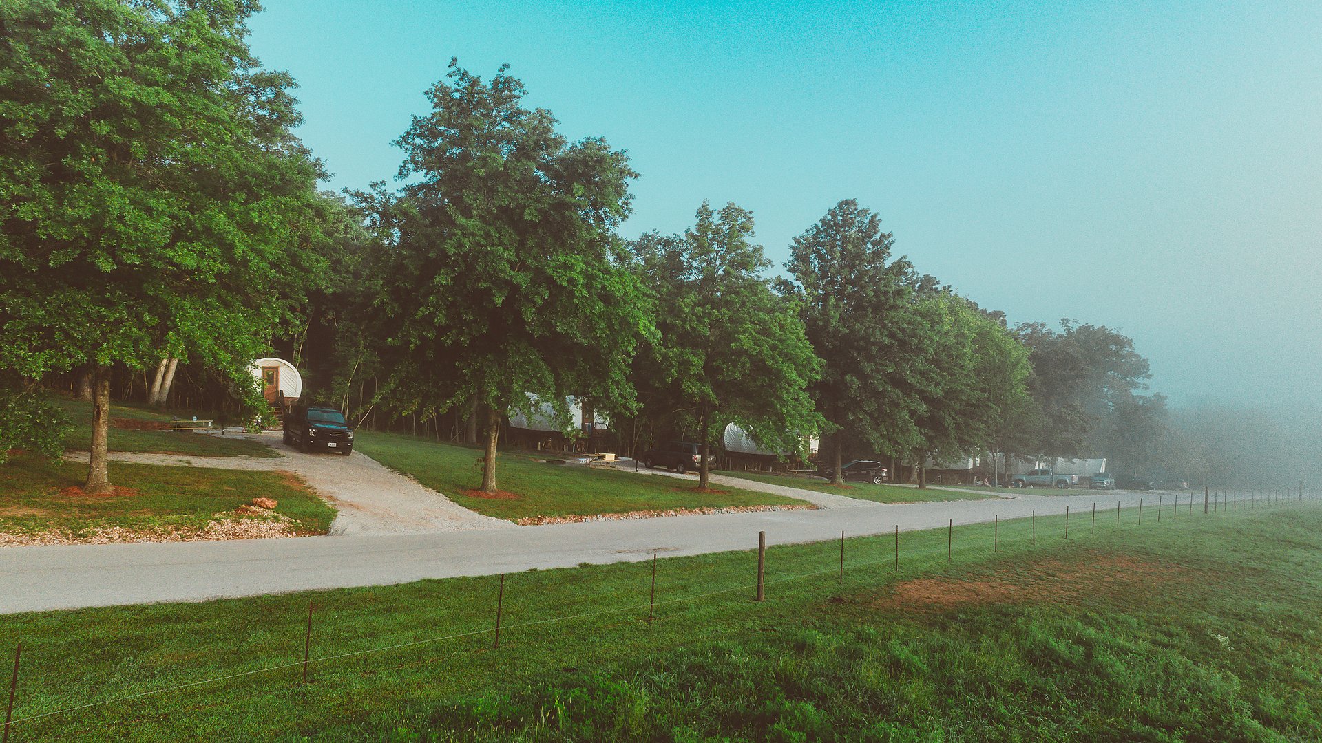 The road curving past covered wagons and RV sites in the early morning.