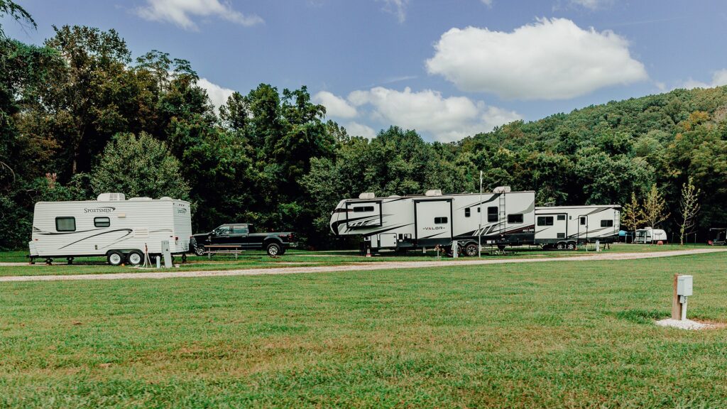 Travel trailers on full-hookup RV sites with the wooded ridge behind.