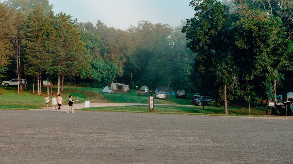 Guests walking toward the tent camping area across the gravel lot.