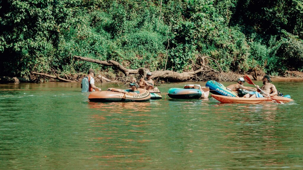 Tubes and a kayak tied together drifting down the river.