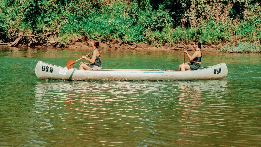 Two guests paddling a Blue Springs Ranch canoe on the green water.