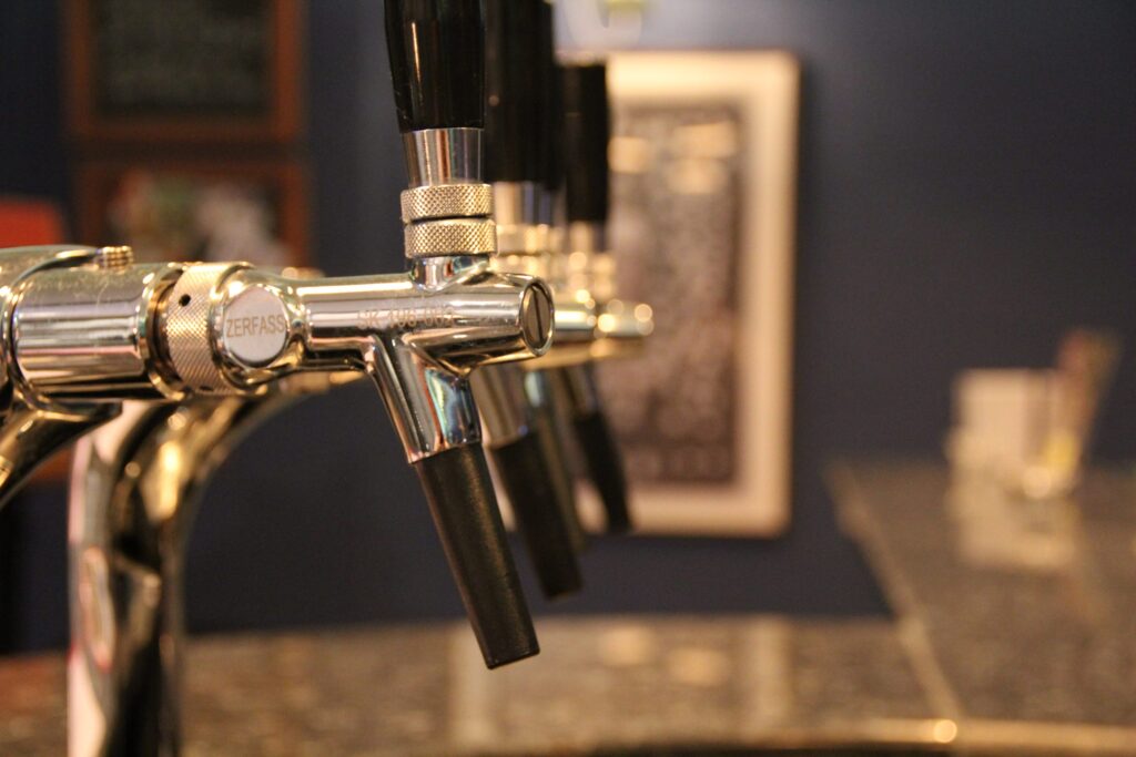 A row of chrome beer taps behind a bar.
